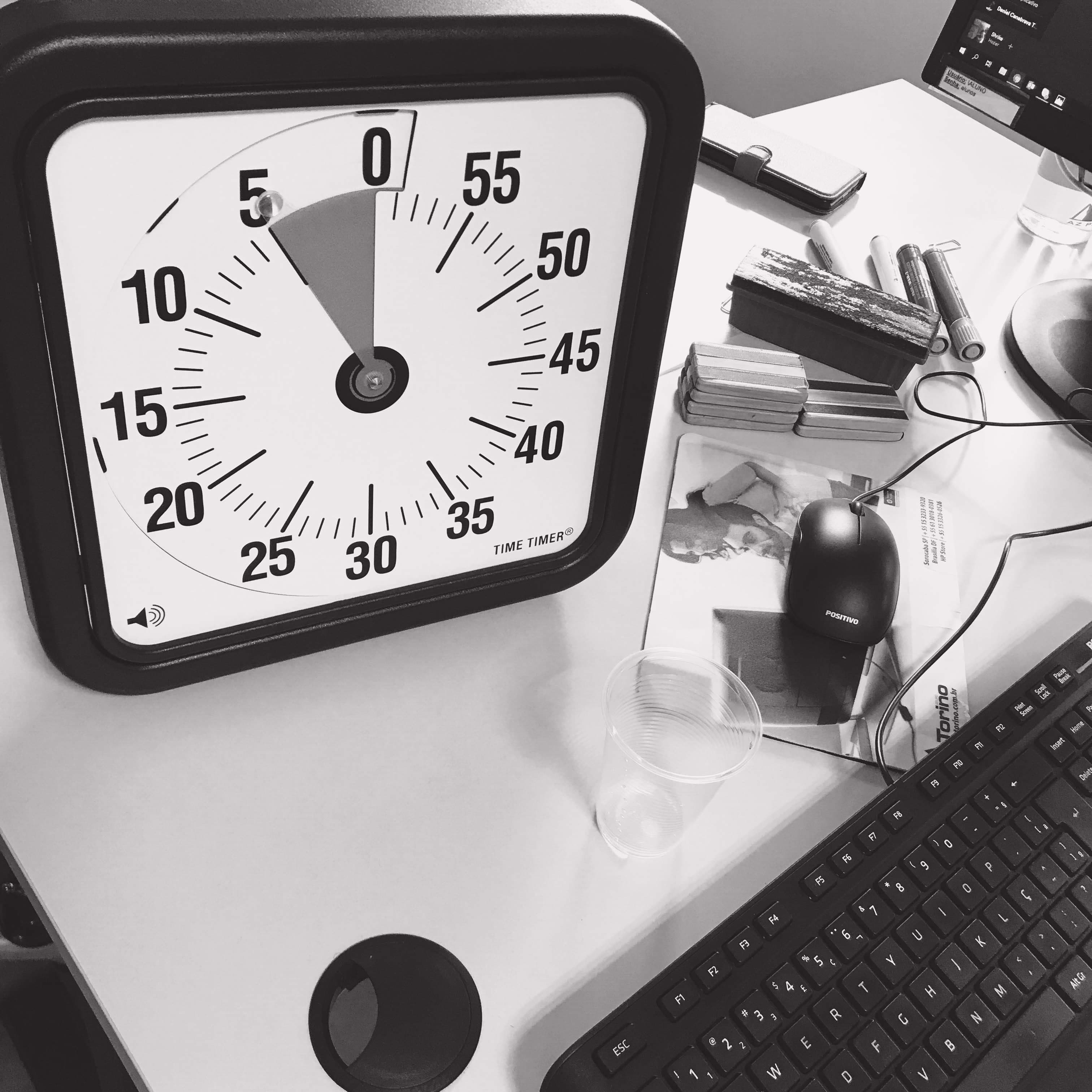 Black-and-white still life of a wall clock on a desk