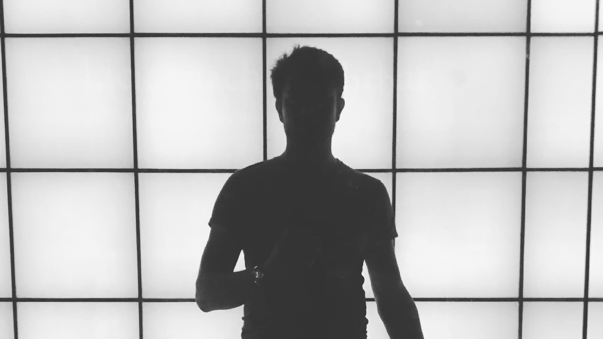 Silhouette of Daniel against a lit grid wall