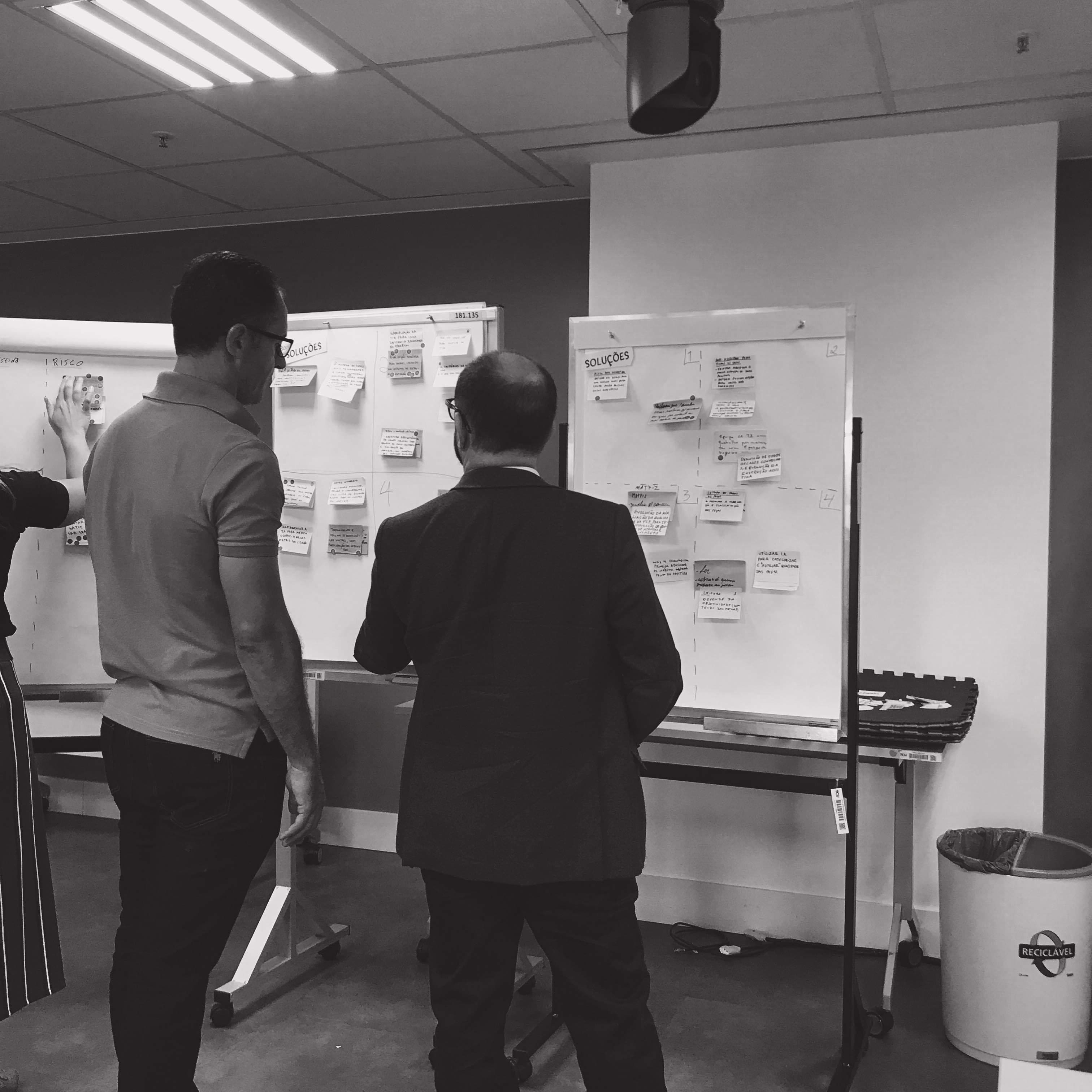 Two auditors reviewing workshop boards covered in notes